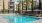 a pool with chairs and umbrellas by a building